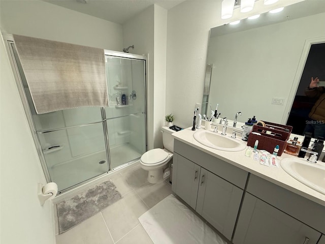 bathroom featuring tile patterned flooring, vanity, a shower with shower door, and toilet