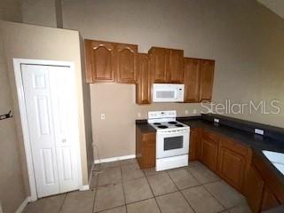 kitchen featuring white appliances and light tile patterned flooring