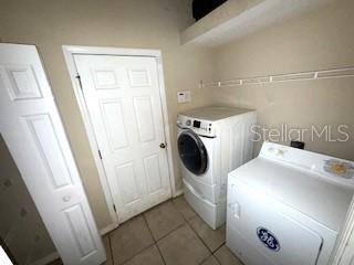 clothes washing area with independent washer and dryer and light tile patterned floors