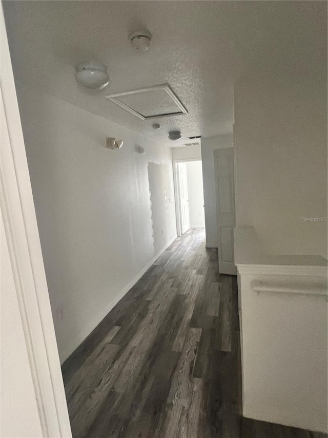 hallway with dark hardwood / wood-style floors and a textured ceiling