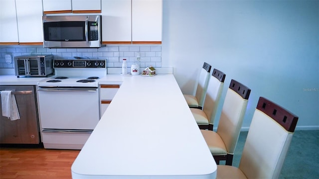 kitchen featuring white cabinets, electric range, tasteful backsplash, and light hardwood / wood-style flooring