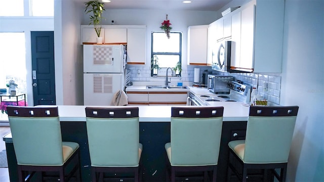 kitchen featuring appliances with stainless steel finishes, tasteful backsplash, white cabinetry, and sink