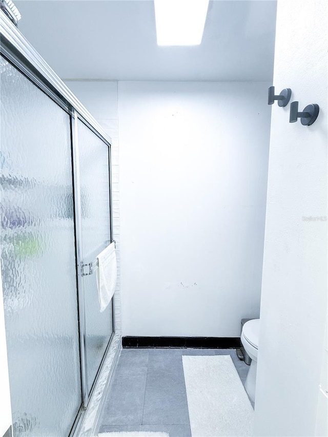 bathroom with a shower with shower door and toilet