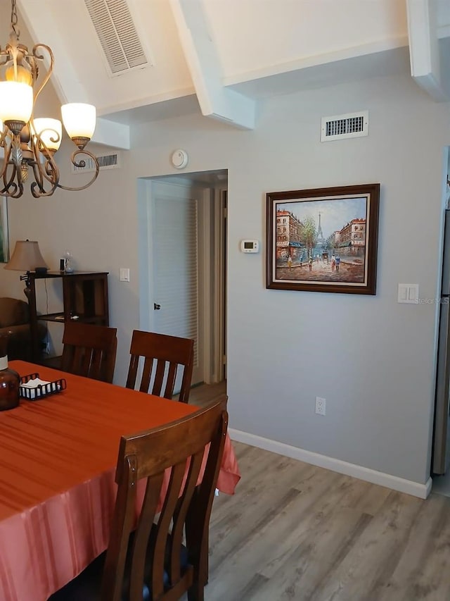 dining space featuring beam ceiling, an inviting chandelier, and hardwood / wood-style floors