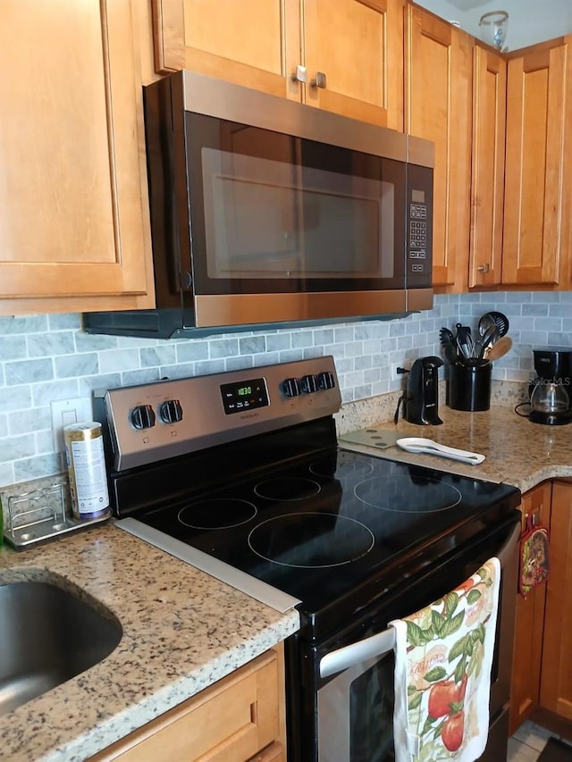 kitchen with decorative backsplash, light stone counters, and stainless steel appliances