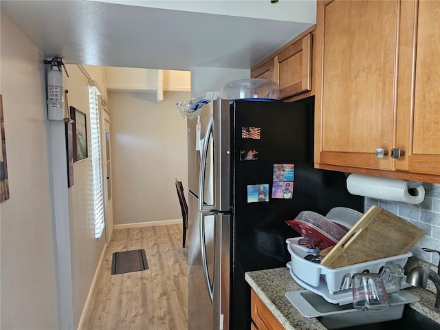 kitchen with a healthy amount of sunlight, light wood-type flooring, and light stone countertops