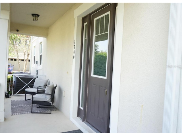 doorway to property featuring a porch and central AC