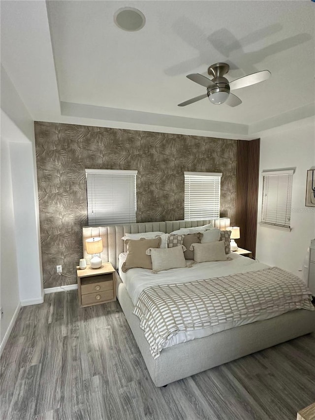 bedroom featuring ceiling fan, dark hardwood / wood-style flooring, and a raised ceiling