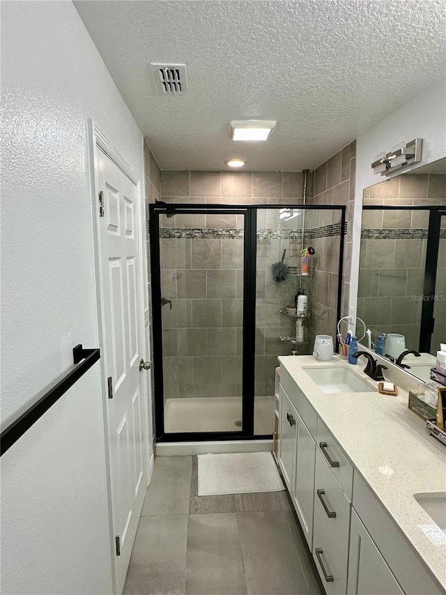 bathroom featuring vanity, a shower with shower door, and a textured ceiling