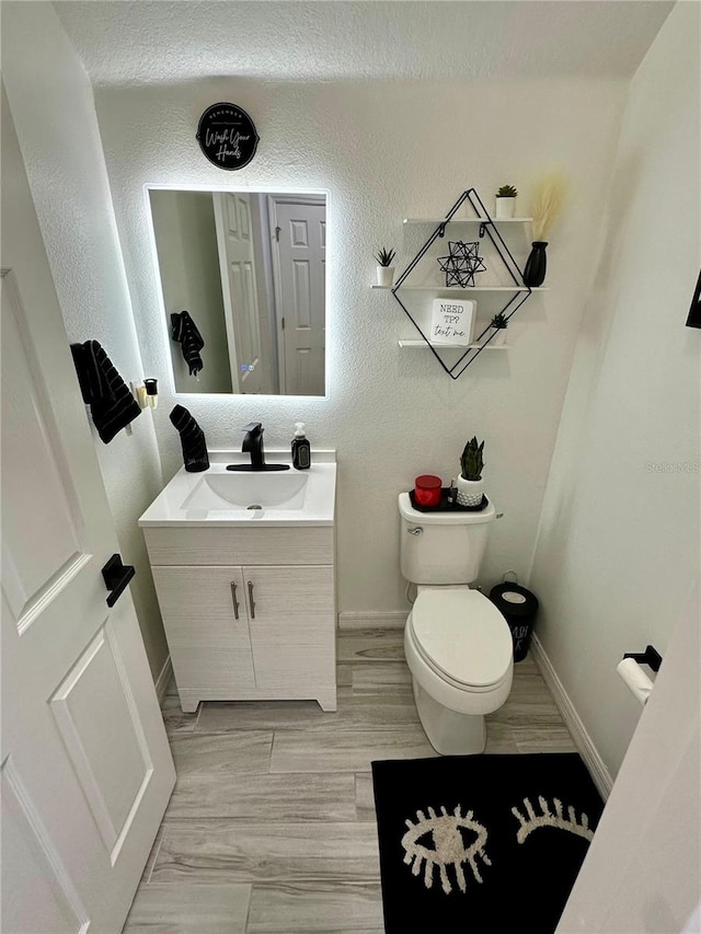 bathroom with hardwood / wood-style floors, vanity, a textured ceiling, and toilet