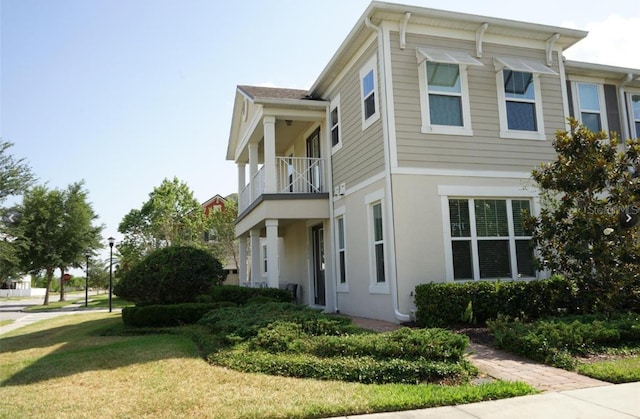 view of side of property with a yard and a balcony