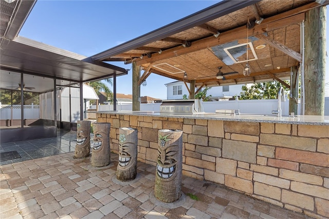 view of patio / terrace featuring grilling area, ceiling fan, sink, and a sunroom