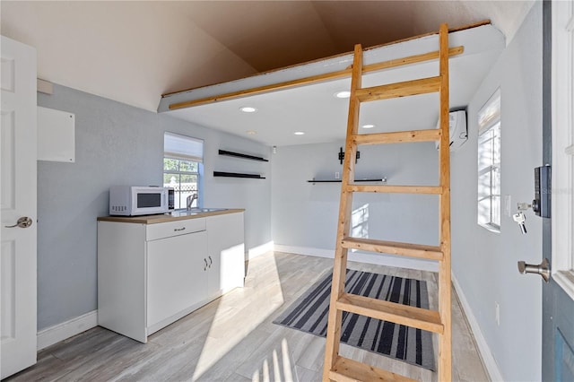 kitchen with white cabinets, lofted ceiling, light wood-type flooring, and sink