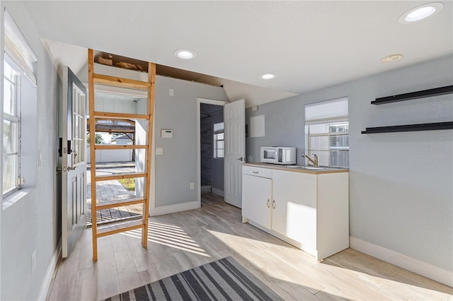 kitchen featuring white cabinets, sink, a wealth of natural light, and light hardwood / wood-style flooring