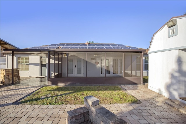 rear view of house with solar panels, a yard, and french doors