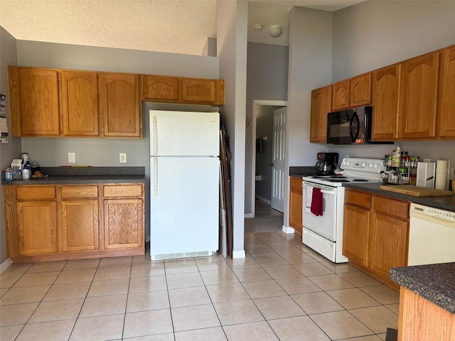 kitchen with light tile patterned floors, white appliances, a textured ceiling, and a high ceiling