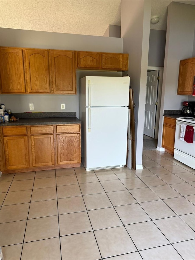 kitchen featuring white appliances, a textured ceiling, light tile patterned floors, and a towering ceiling