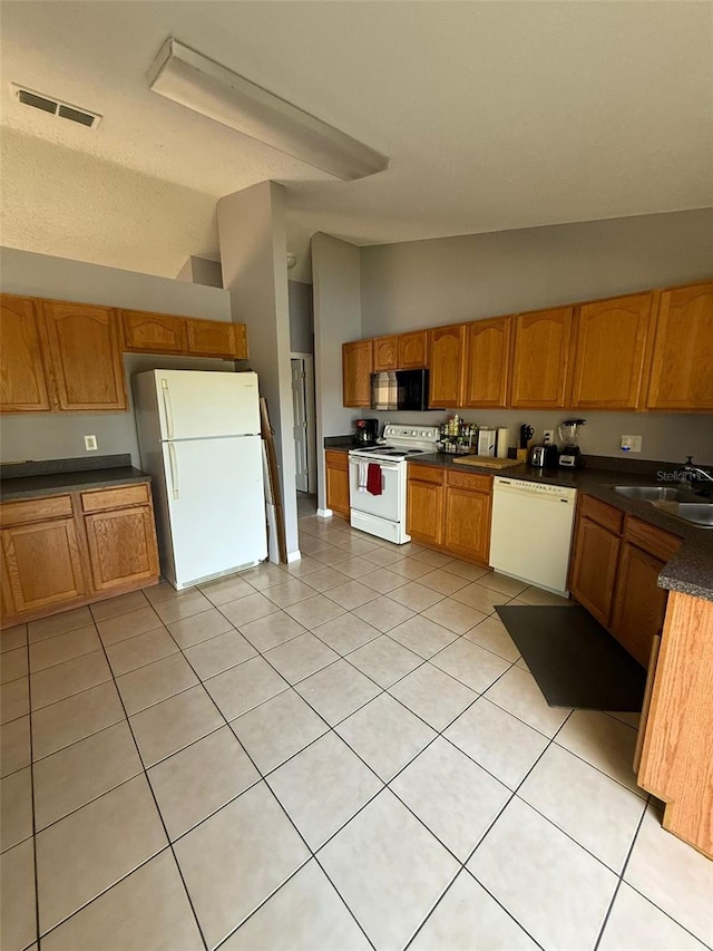 kitchen featuring lofted ceiling, sink, light tile patterned flooring, and white appliances