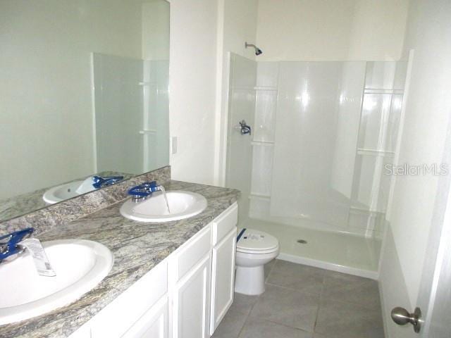 bathroom featuring a shower, tile patterned flooring, vanity, and toilet