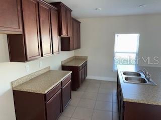 kitchen featuring sink, light tile patterned floors, and dark brown cabinets