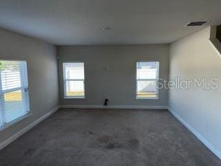 empty room featuring dark colored carpet and plenty of natural light