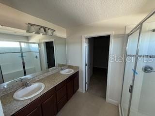 bathroom featuring vanity, a textured ceiling, and a shower with shower door