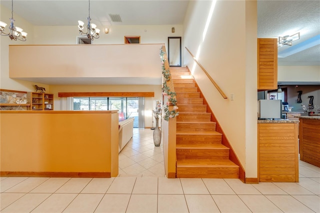 stairway featuring tile patterned flooring, a textured ceiling, and an inviting chandelier