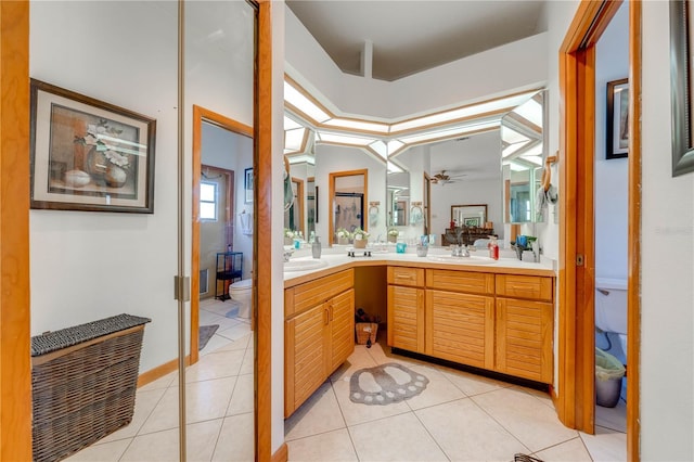 bathroom featuring ceiling fan, tile patterned flooring, lofted ceiling, toilet, and vanity