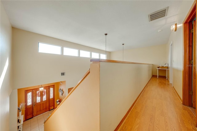 hall with light hardwood / wood-style floors and a high ceiling