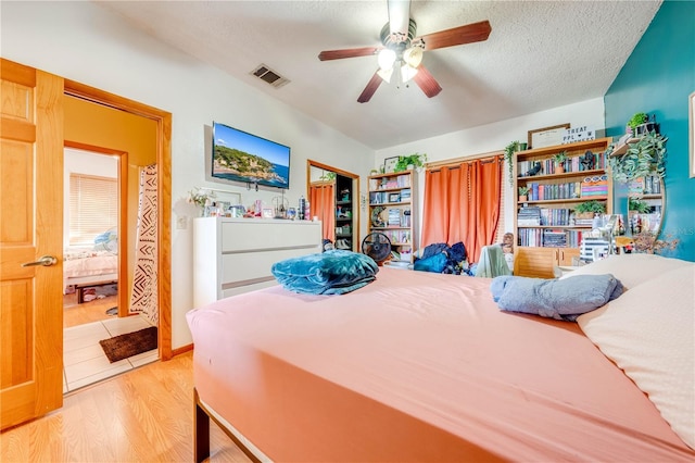 bedroom with a textured ceiling, light wood-type flooring, and ceiling fan