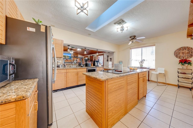 kitchen with light tile patterned floors, a textured ceiling, black electric cooktop, and light stone counters