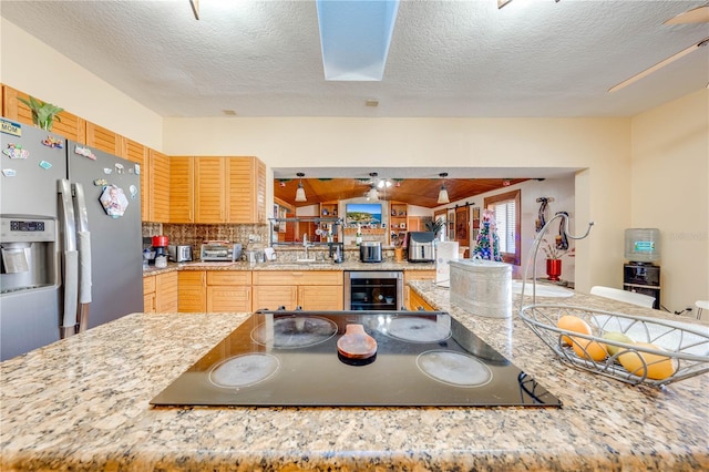 kitchen featuring light brown cabinets, wine cooler, stainless steel refrigerator with ice dispenser, a textured ceiling, and black electric stovetop