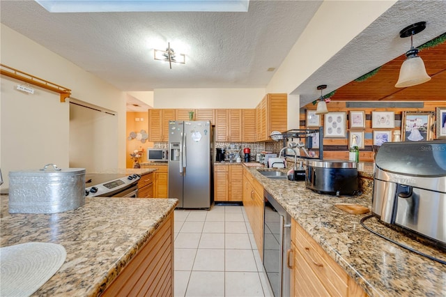 kitchen with sink, light stone counters, light brown cabinetry, light tile patterned flooring, and appliances with stainless steel finishes