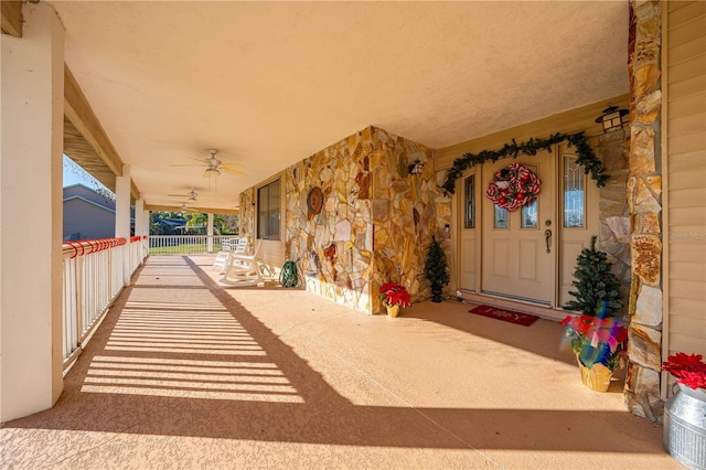 view of exterior entry featuring ceiling fan and covered porch