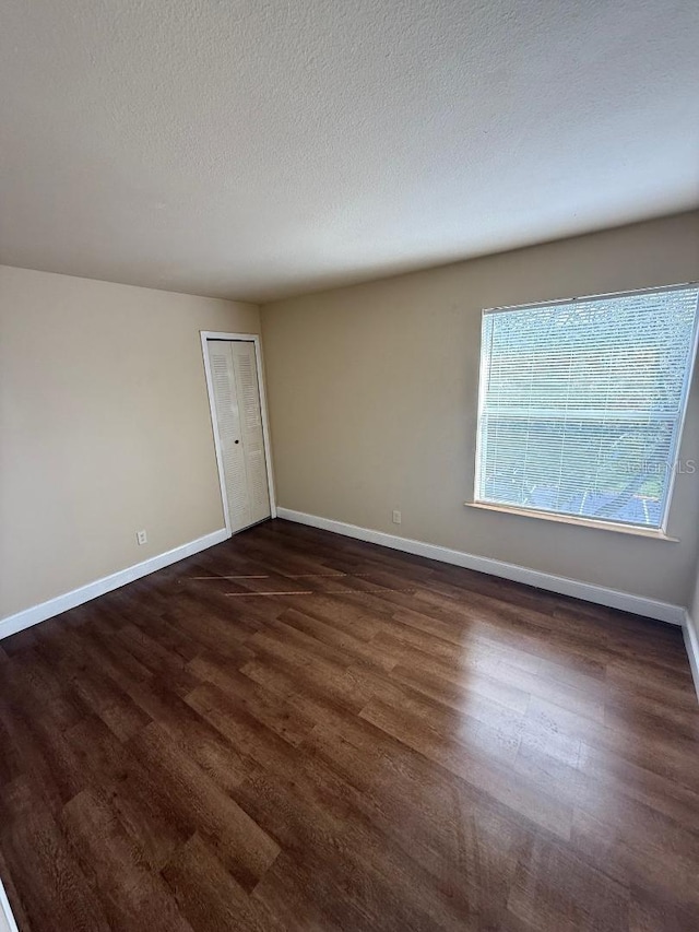 empty room with dark hardwood / wood-style flooring and a textured ceiling