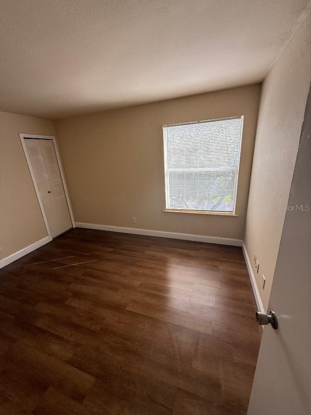 unfurnished room with dark hardwood / wood-style flooring and a textured ceiling