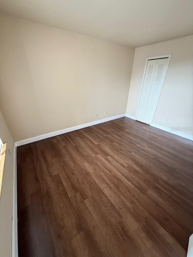 unfurnished bedroom with dark hardwood / wood-style floors and a closet