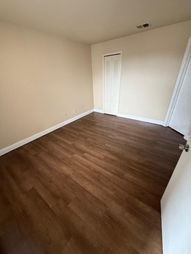 unfurnished bedroom with dark wood-type flooring and a closet