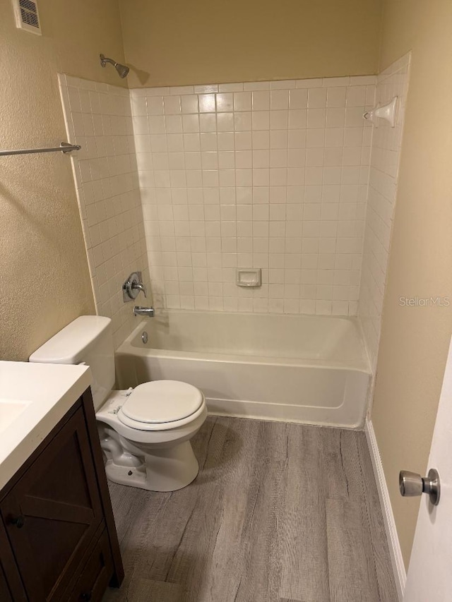 full bathroom with vanity, toilet, wood-type flooring, and tiled shower / bath