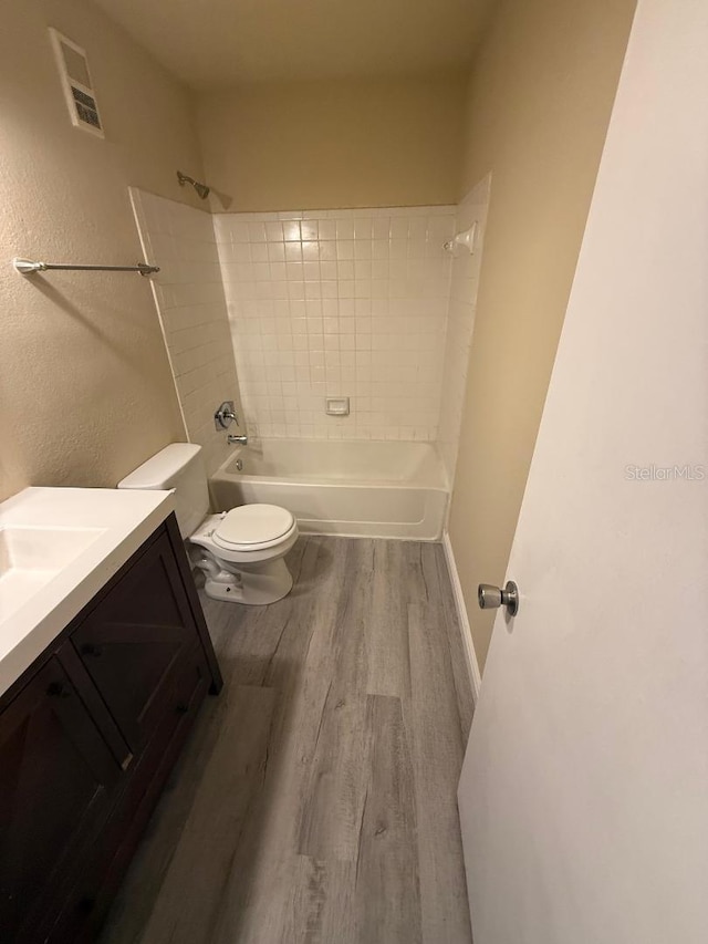 full bathroom featuring hardwood / wood-style floors, vanity, tiled shower / bath combo, and toilet