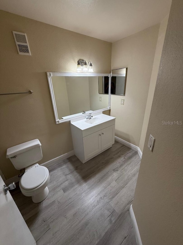 bathroom with hardwood / wood-style floors, vanity, and toilet