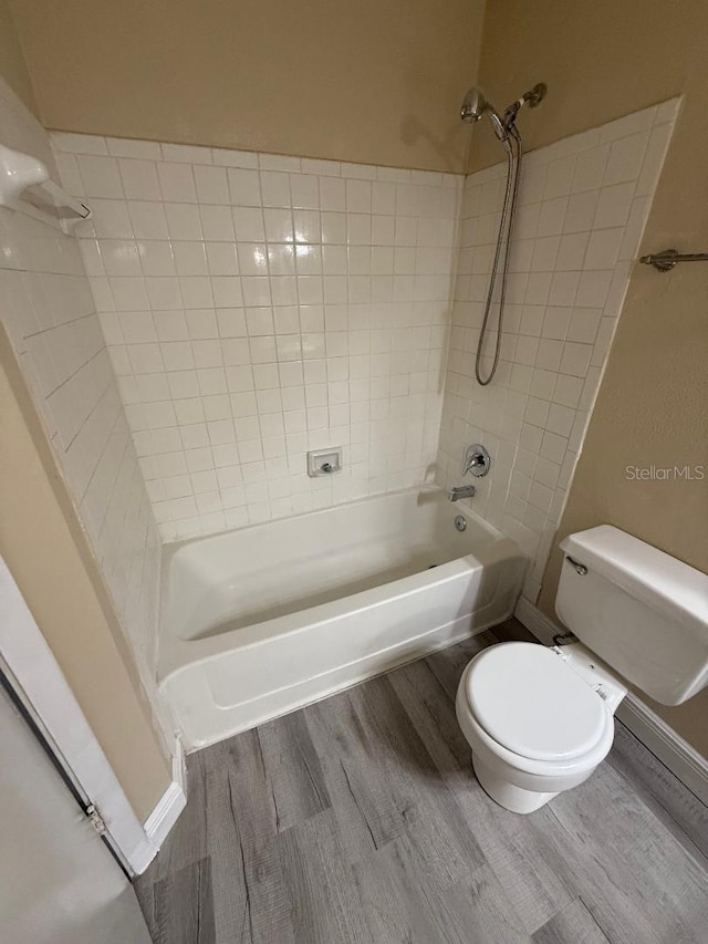 bathroom featuring hardwood / wood-style flooring, toilet, and tiled shower / bath