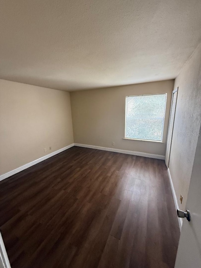 unfurnished room featuring a textured ceiling and dark wood-type flooring