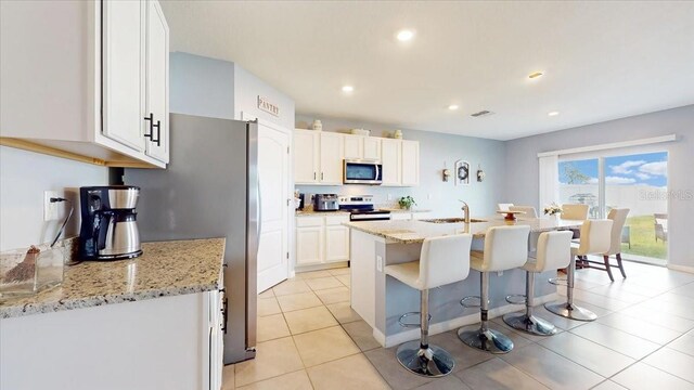 kitchen featuring light stone countertops, sink, white cabinets, and appliances with stainless steel finishes