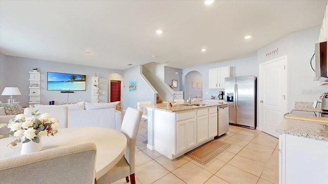 kitchen featuring white cabinetry, sink, a center island with sink, light tile patterned floors, and appliances with stainless steel finishes