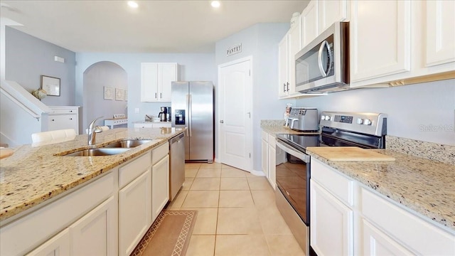 kitchen with light stone countertops, sink, stainless steel appliances, light tile patterned floors, and white cabinets