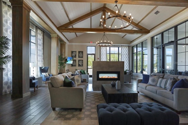 living room featuring beam ceiling, a healthy amount of sunlight, dark wood-type flooring, and a chandelier