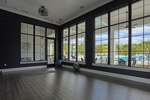 workout area featuring ceiling fan, a healthy amount of sunlight, wood-type flooring, and crown molding