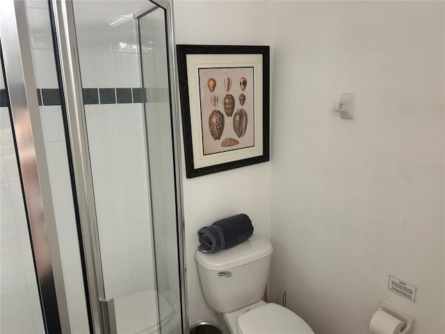 bathroom featuring toilet and a shower with shower door