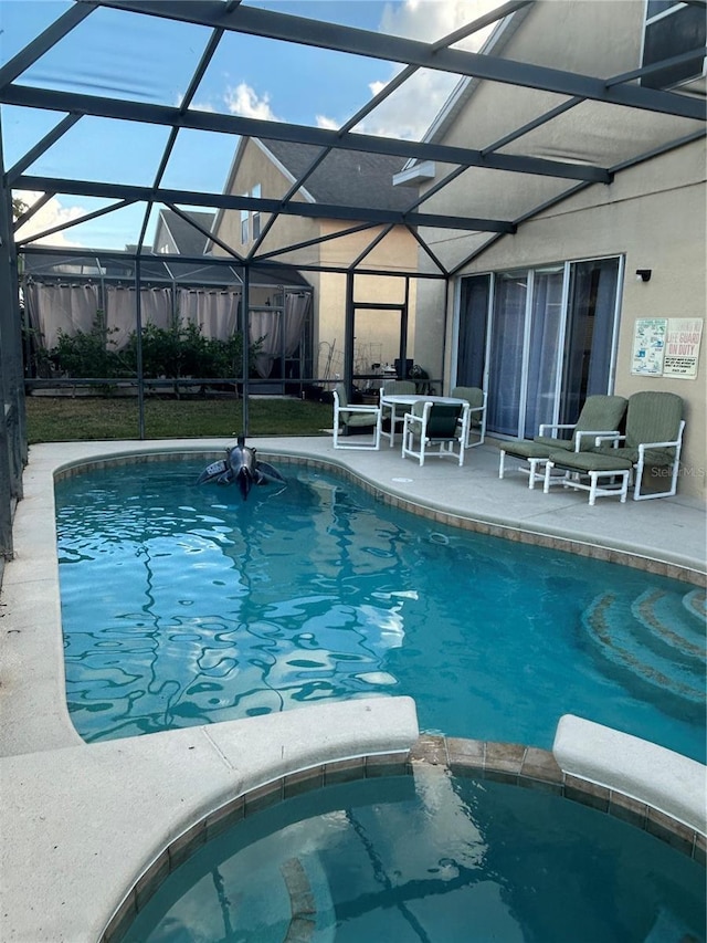 view of pool featuring glass enclosure and a patio